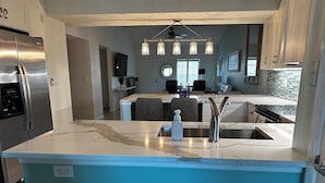 A modern kitchen with a central island, stainless steel appliances, and a blue accent wall. - 2 Bed + Den condo in charming Naples with, private pool, WiFi. Relax and unwind (Naples)