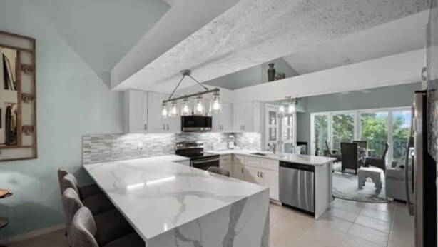 A modern kitchen with a large marble island, stainless steel appliances, and a pendant light fixture. - 2 Bed + Den condo in charming Naples with, private pool, WiFi. Relax and unwind (Naples)