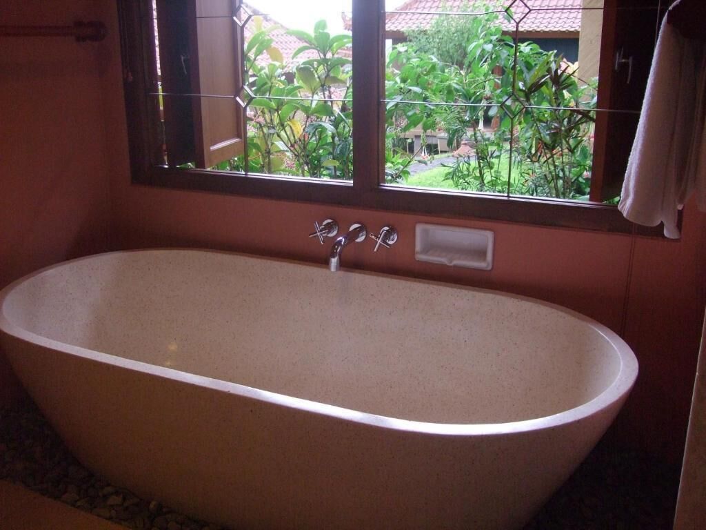 A large freestanding bathtub in a bathroom with a window.