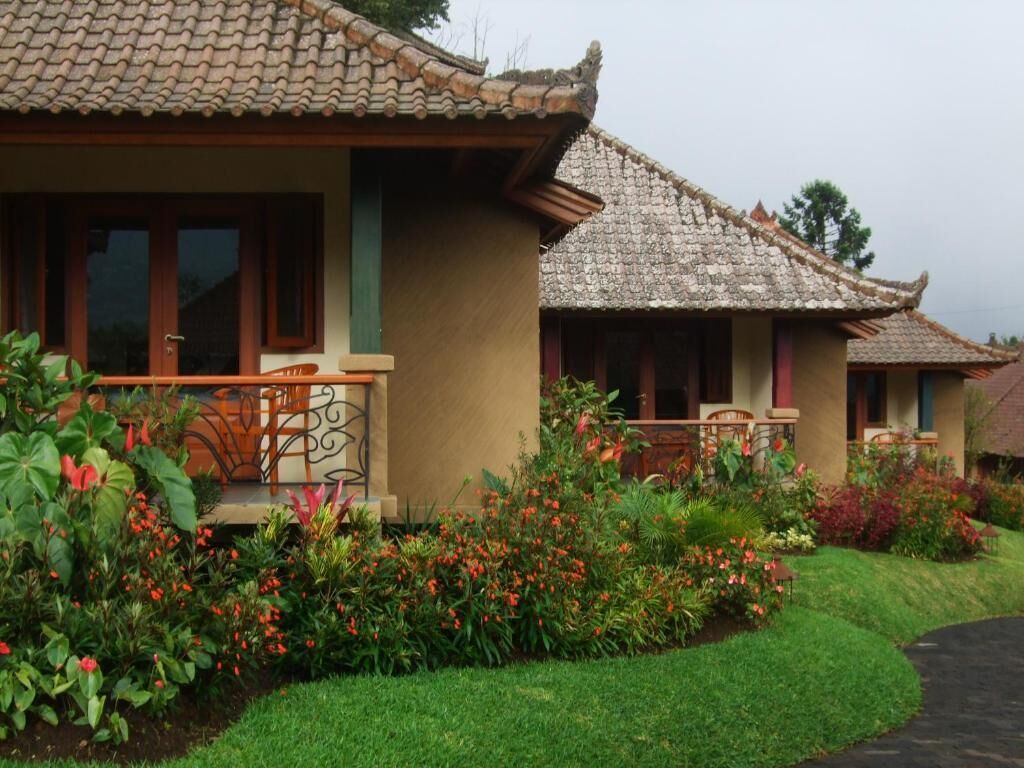 A traditional building with a tiled roof, a balcony with a railing, and a well-maintained garden with various plants and flowers.