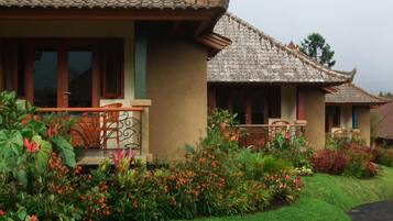 A traditional building with a tiled roof, a balcony with a railing, and a well-maintained garden with various plants and flowers.