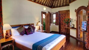Quarto bem organizado com cama de madeira, duas mesas de cabeceira com luminárias, uma televisão e uma escrivaninha com cadeira.