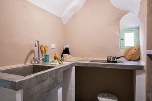 Een koelkast, een kookplaat, kookgerei, borden en bestek