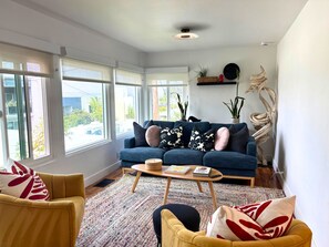 A modern living room with a blue sofa, yellow armchairs, and a coffee table. - Golden Hour House OB (San Diego)
