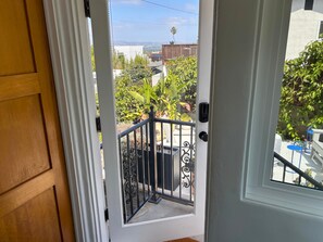 A view from a balcony with a metal railing, a door, and a window.