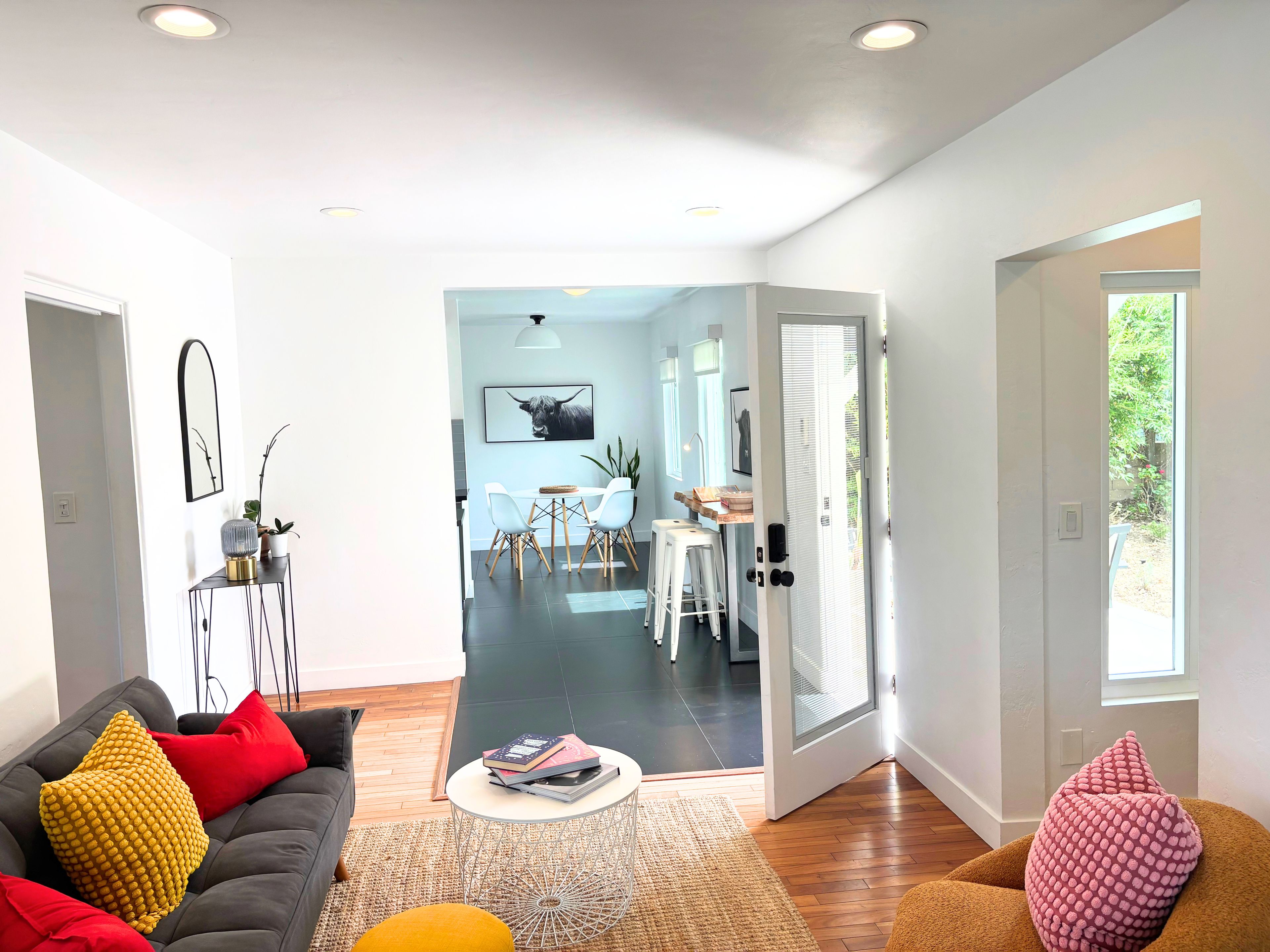 A modern living room with a sofa, coffee table, and a dining area with a table and chairs.