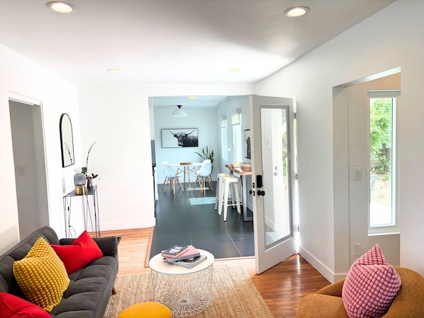 A modern living room with a sofa, coffee table, and a dining area with a table and chairs.