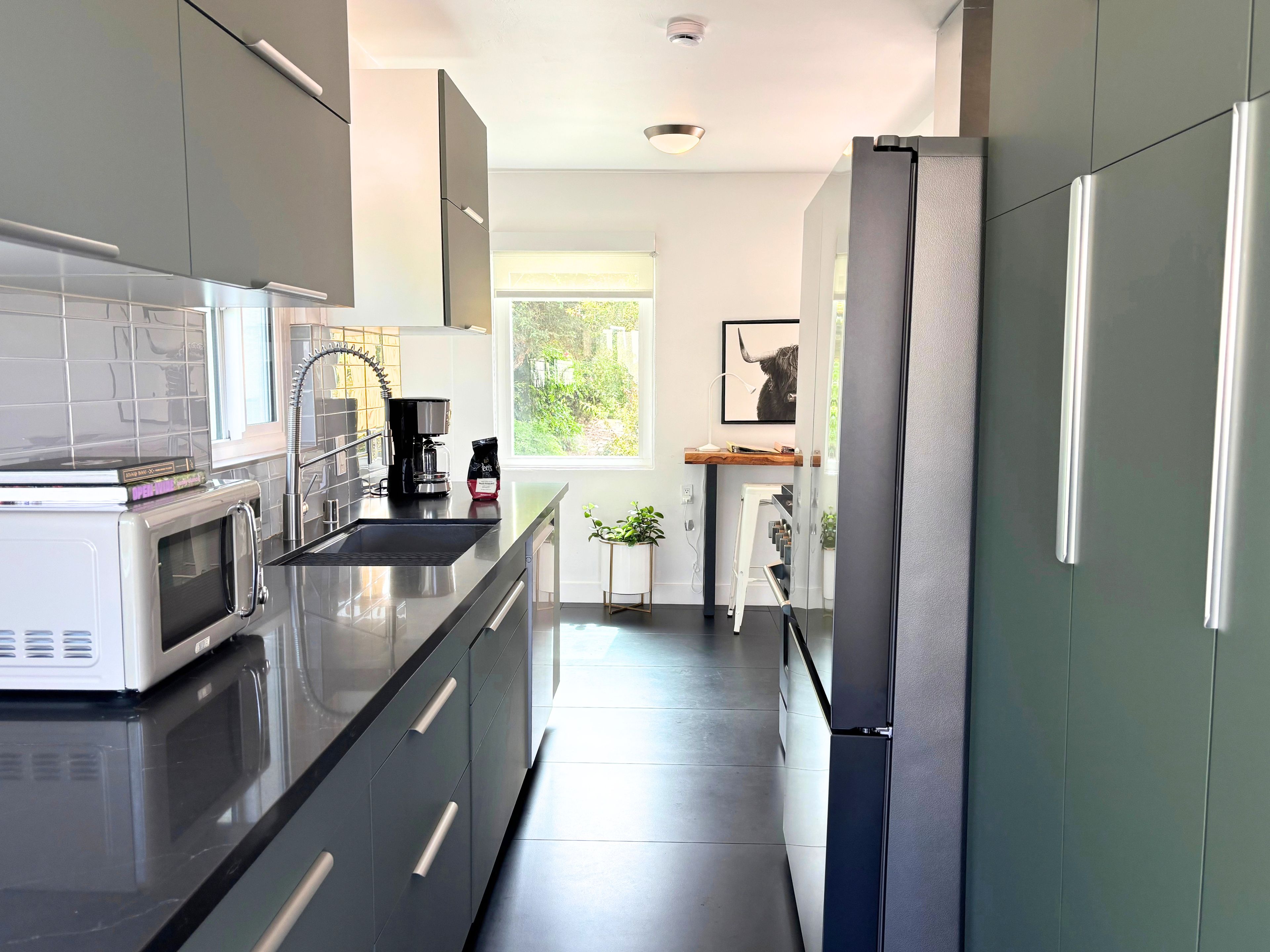 A modern kitchen with a microwave, coffee maker, and refrigerator.