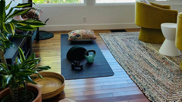 A spacious room with large windows, a yoga mat, kettlebell, and a potted plant. - Zen Point Loma Garden House (San Diego)