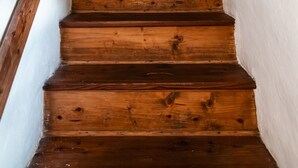 A wooden staircase with a rustic design, leading to a room with a white wall and a circular decorative item on the wall. - Gorenja Trebuša, Domačija Gačnik (Tolmin)