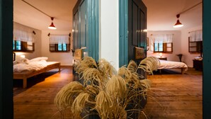A room with a wooden floor, two beds, a blue wall, and a central column with a plant. - Gorenja Trebuša, Domačija Gačnik (Tolmin)