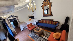 A room with a sofa, armchair, and a bed. There is a mirror on the wall and a chandelier. - Cozy loft in the historic center with washing machine (Cusco)