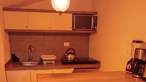 A compact kitchen with a microwave, kettle, coffee maker, and a bar stool. - Cozy loft in the historic center with washing machine (Cusco)