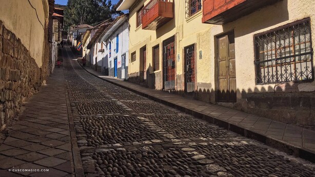 A cobblestone street lined with traditional buildings, featuring balconies with wooden railings and barred windows. - Cozy loft in the historic center with washing machine (Cusco)