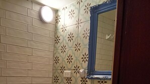A bathroom with a toilet, sink, and mirror. The walls are tiled with a floral pattern. - Cozy loft in the historic center with washing machine (Cusco)