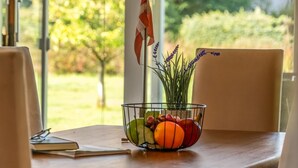A dining table with a fruit bowl, a flag, and a window with a view of trees. - "Galmand" -  from the sea by Interhome (Hals)