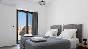 Ett modernt hotellrum med två sängar, ett stort fönster och utsikt över en stenmur.
