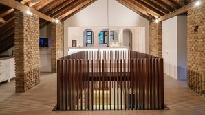 A modern interior with exposed wooden beams, brick walls, and a central seating area with vertical slats. - La moderna suites (Málaga)