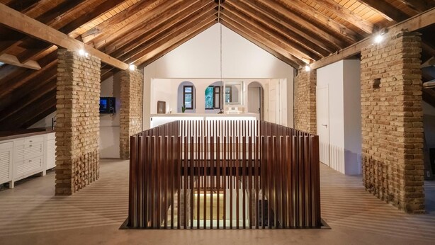 A modern interior with exposed wooden beams, a central seating area, and stone pillars. - La moderna suites (Málaga)