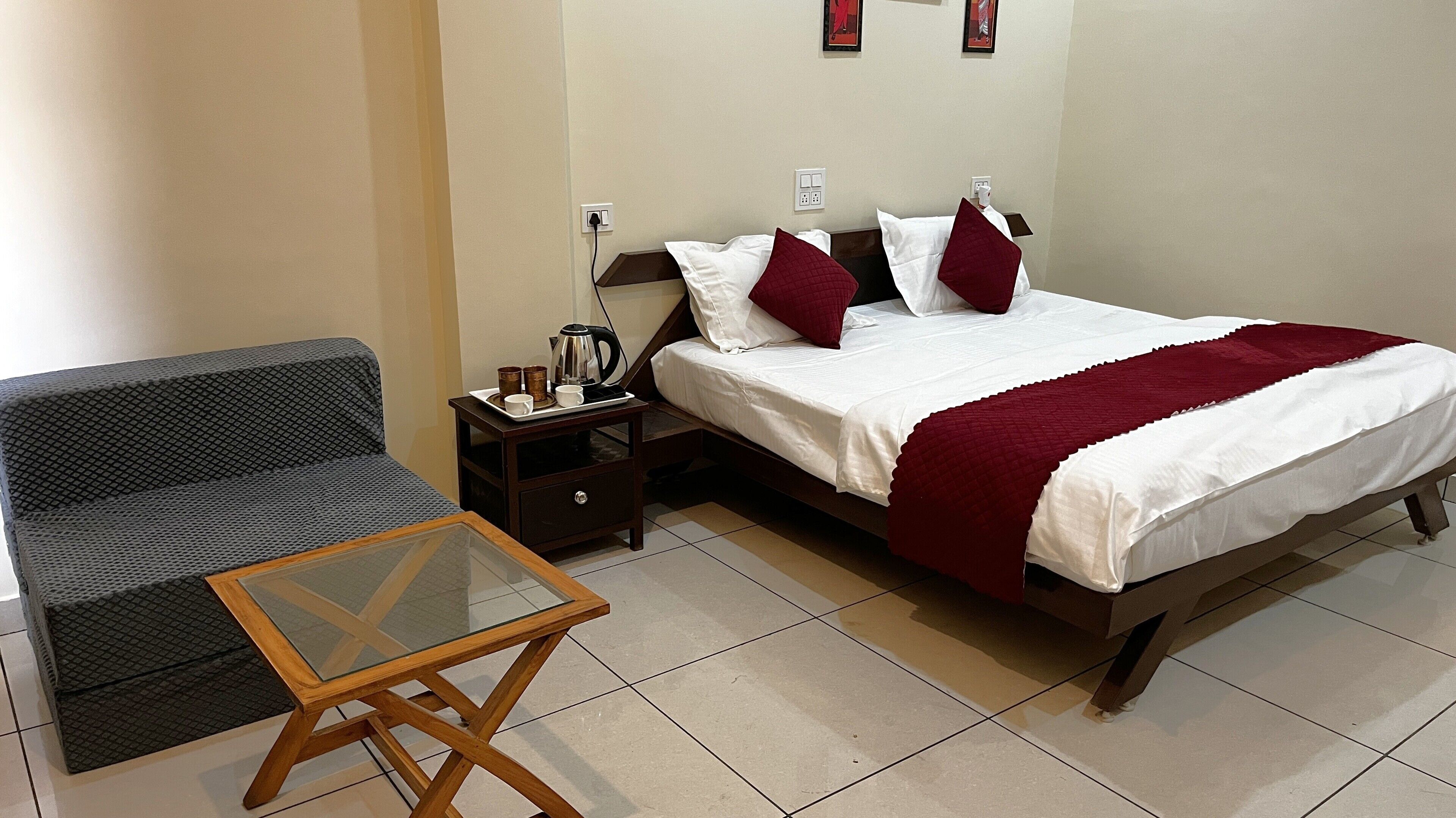 Ein Hotelzimmer mit Bett, Schlafsofa, Nachttisch und Glastisch.