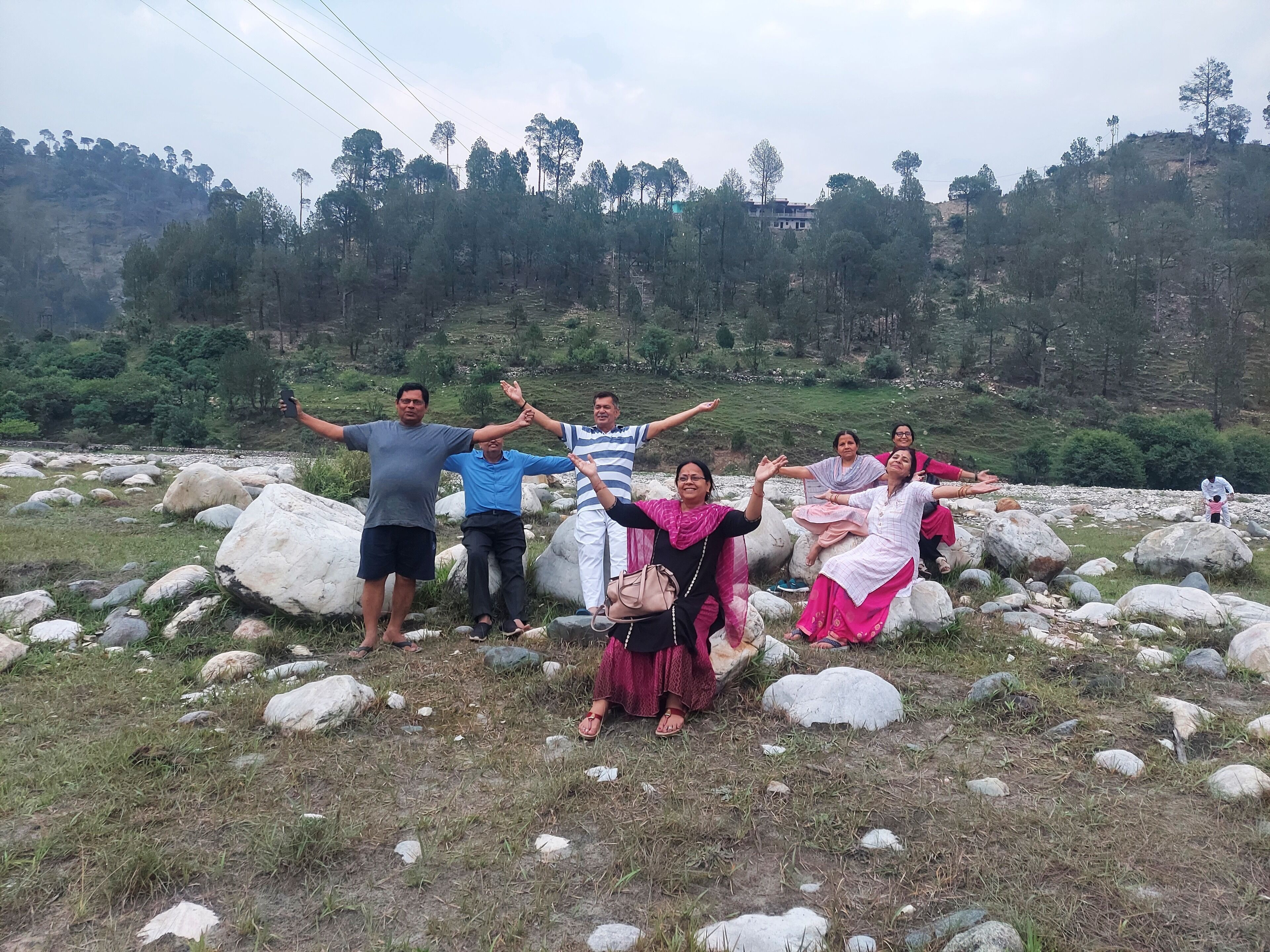 Un grupo de personas posando sobre un terreno rocoso, con una colina boscosa al fondo.