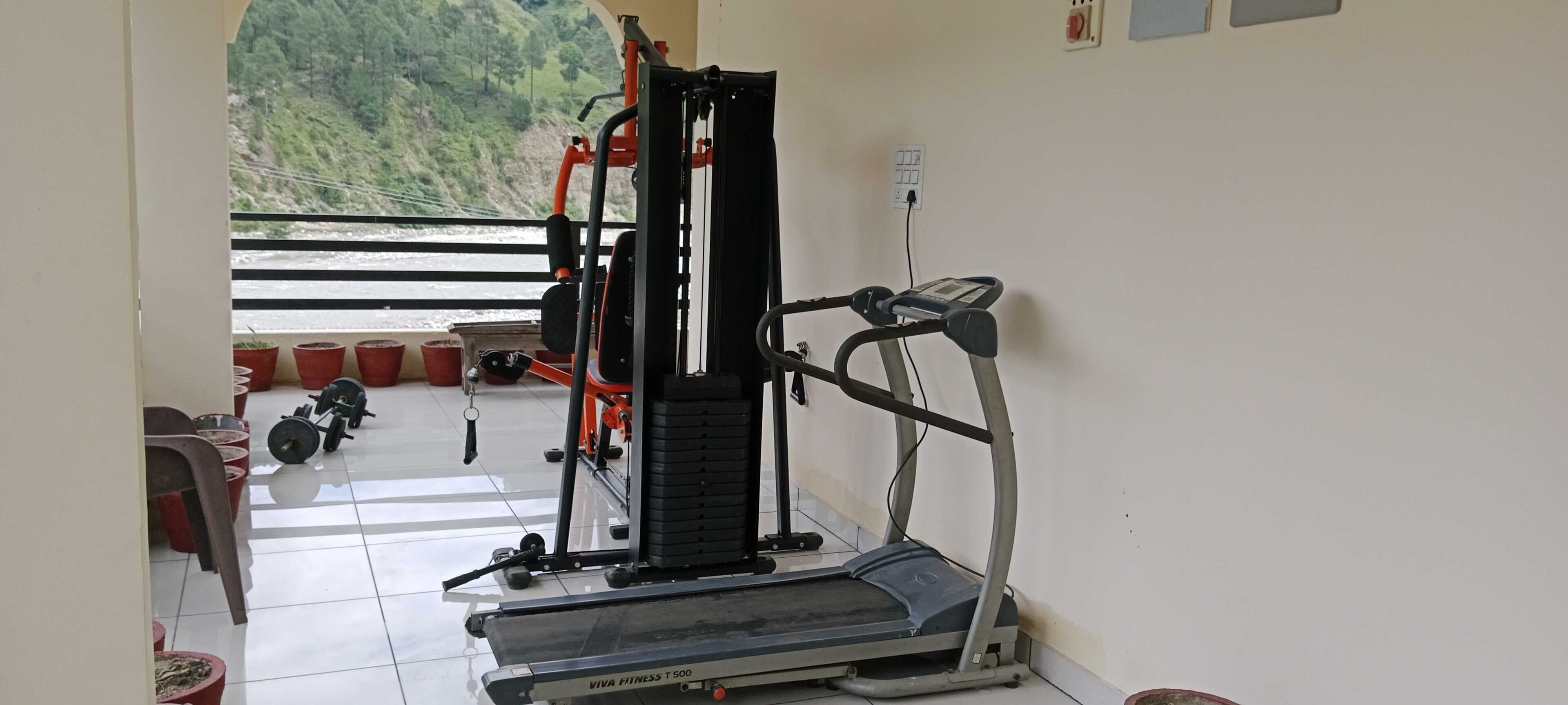Ein Heimfitnessraum mit Laufband, Gewichtbank und Kabelzugmaschine.
