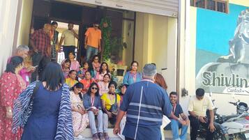 A group of people exiting a building with a sign reading "Shivlinga Villa Contact".