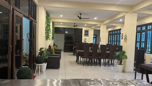 Um hall de hotel espaçoso com várias áreas de estar, ventiladores de teto e design moderno.