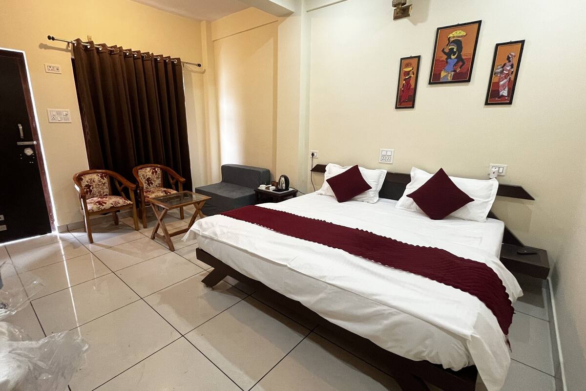 Une chambre d’hôtel avec un lit, deux chaises, un canapé, une table et des œuvres d’art accrochées au mur.