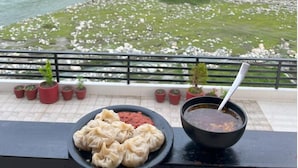 Uma varanda com vista para um rio, um prato de dumplings e uma tigela de sopa.
