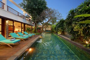 Una piscina al aire libre, sombrillas, sillones reclinables de piscina