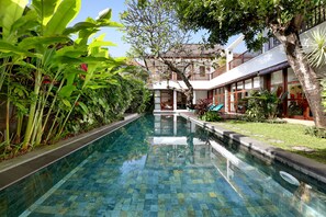 Una piscina al aire libre, sombrillas, sillones reclinables de piscina