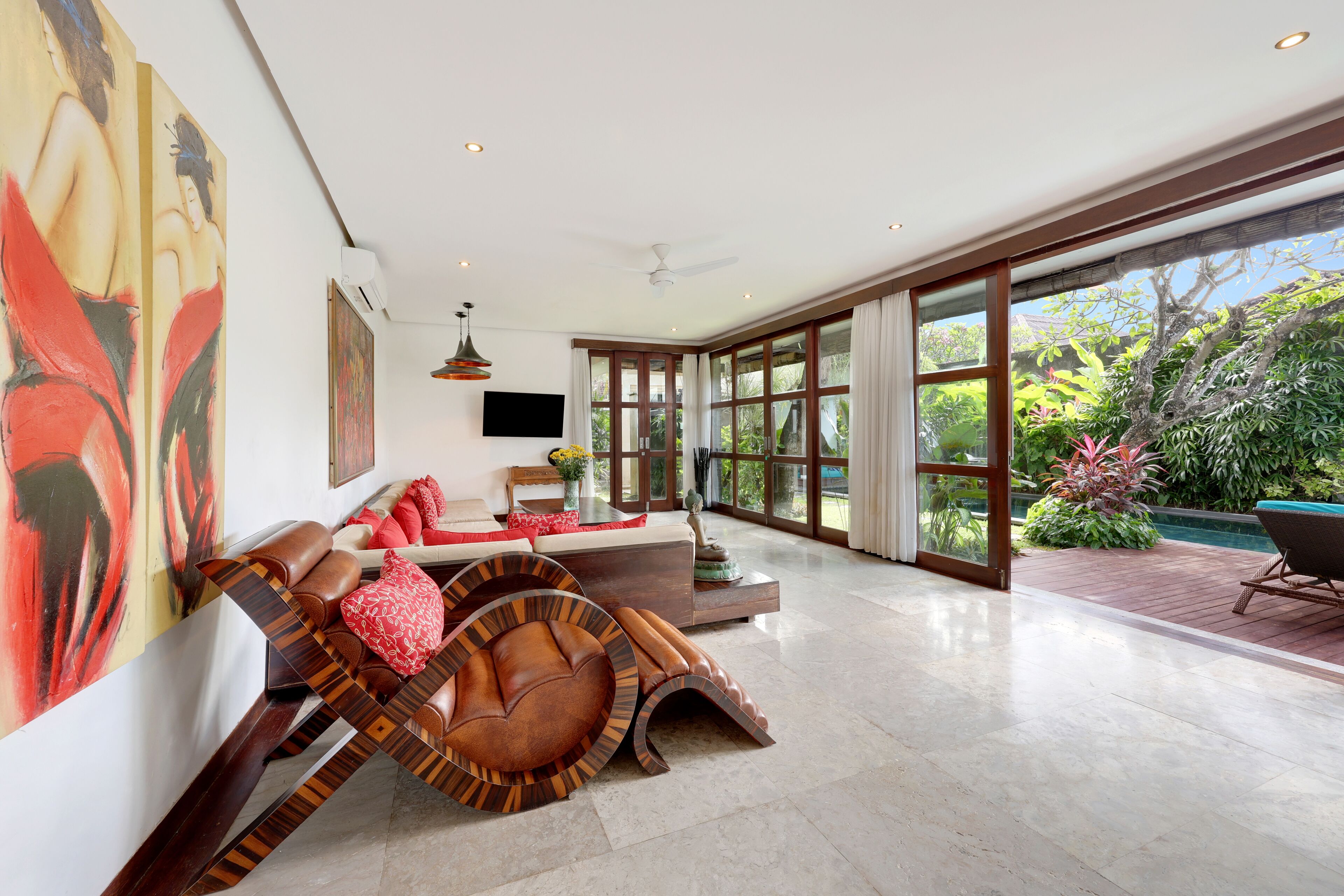 A spacious living room with a large window, a ceiling fan, and a modern sofa.