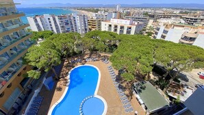 A rooftop pool surrounded by trees and lounge chairs, with a view of the sea and cityscape. - Chic Stay by the Beach (Tarragona)