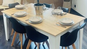 Comedor con una mesa de madera dispuesta para seis personas, rodeada de sillas negras con patas de madera.