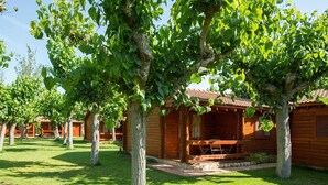Une rangée de cabanes en bois, dotées d’un porche abrité et bordées d’une pelouse verdoyante.