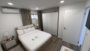 Una habitación de hotel moderna con una cama, mesitas de noche, un armario y un televisor.