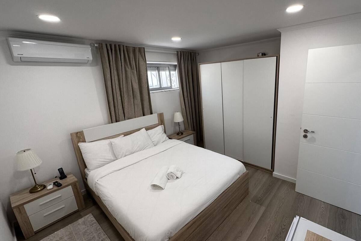 Una camera d'albergo moderna con un letto, comodini, un armadio e una televisione.