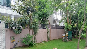 A well-maintained garden with a grassy lawn, a brick wall, and a metal fence. - Welcome Inn Guest House (Islamabad)