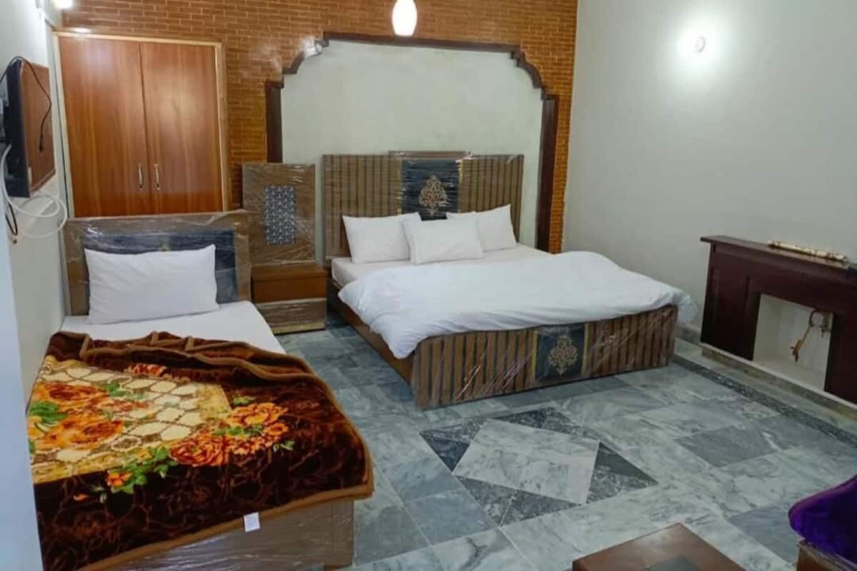 A bedroom with a bed, a wardrobe, a small table, and a decorative headboard.