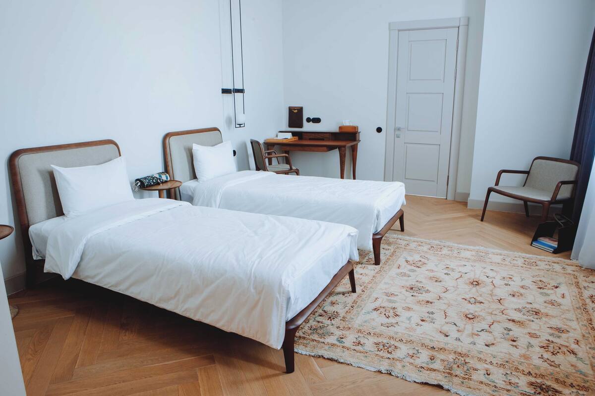 Une chambre avec deux lits simples, un bureau, une chaise et une porte.