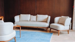A modern living room with a light-colored sofa, a matching armchair, and a wooden coffee table. - Pana Boutique Hotel (Shymkent)