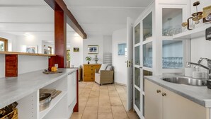 A modern kitchen with a built-in oven, a sink, and a dining area with a wooden table and chairs. - "Darleen" - 850m to the fjord by Interhome (Vemb)