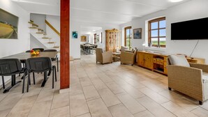 A spacious living area with a dining table, chairs, a sofa, and a TV mounted on the wall. - "Darleen" - 850m to the fjord by Interhome (Vemb)