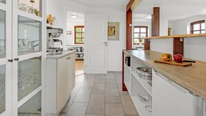 A modern kitchen with white cabinetry, a coffee machine, and a wooden countertop. - "Darleen" - 850m to the fjord by Interhome (Vemb)