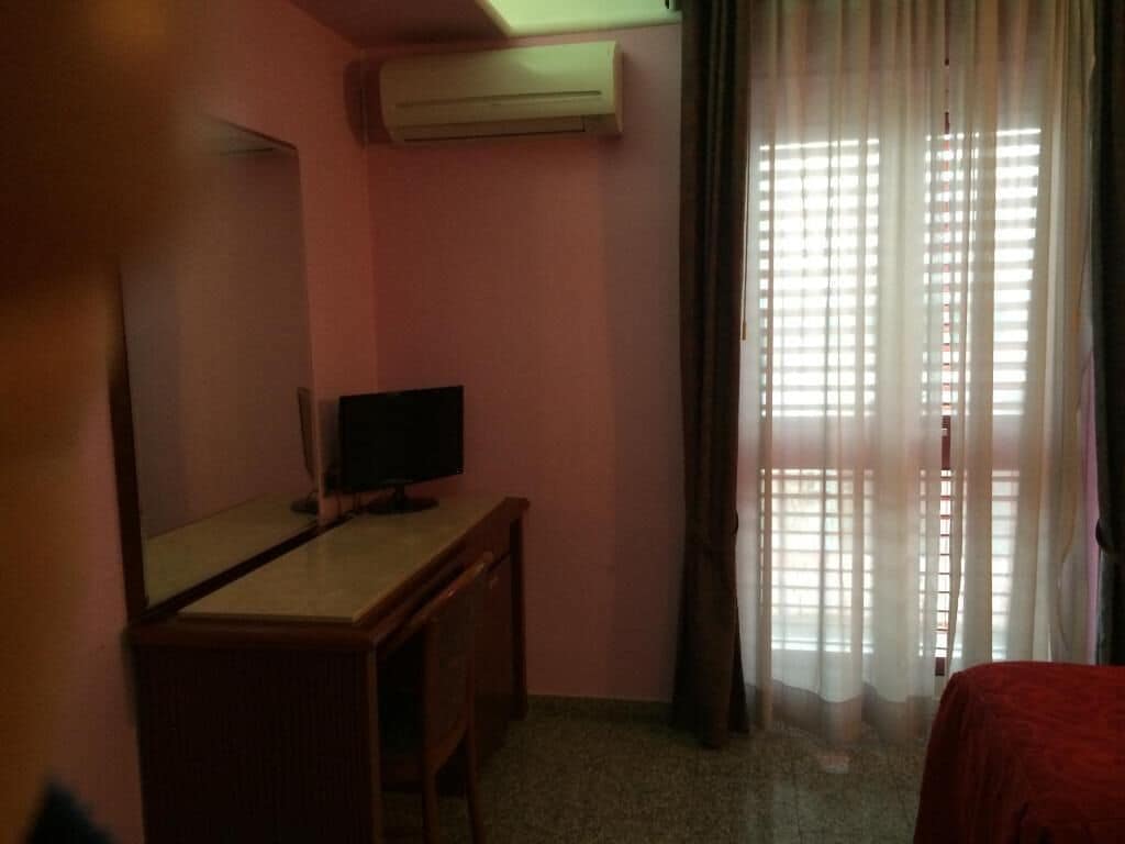 A room with a desk, a television, and a bed.