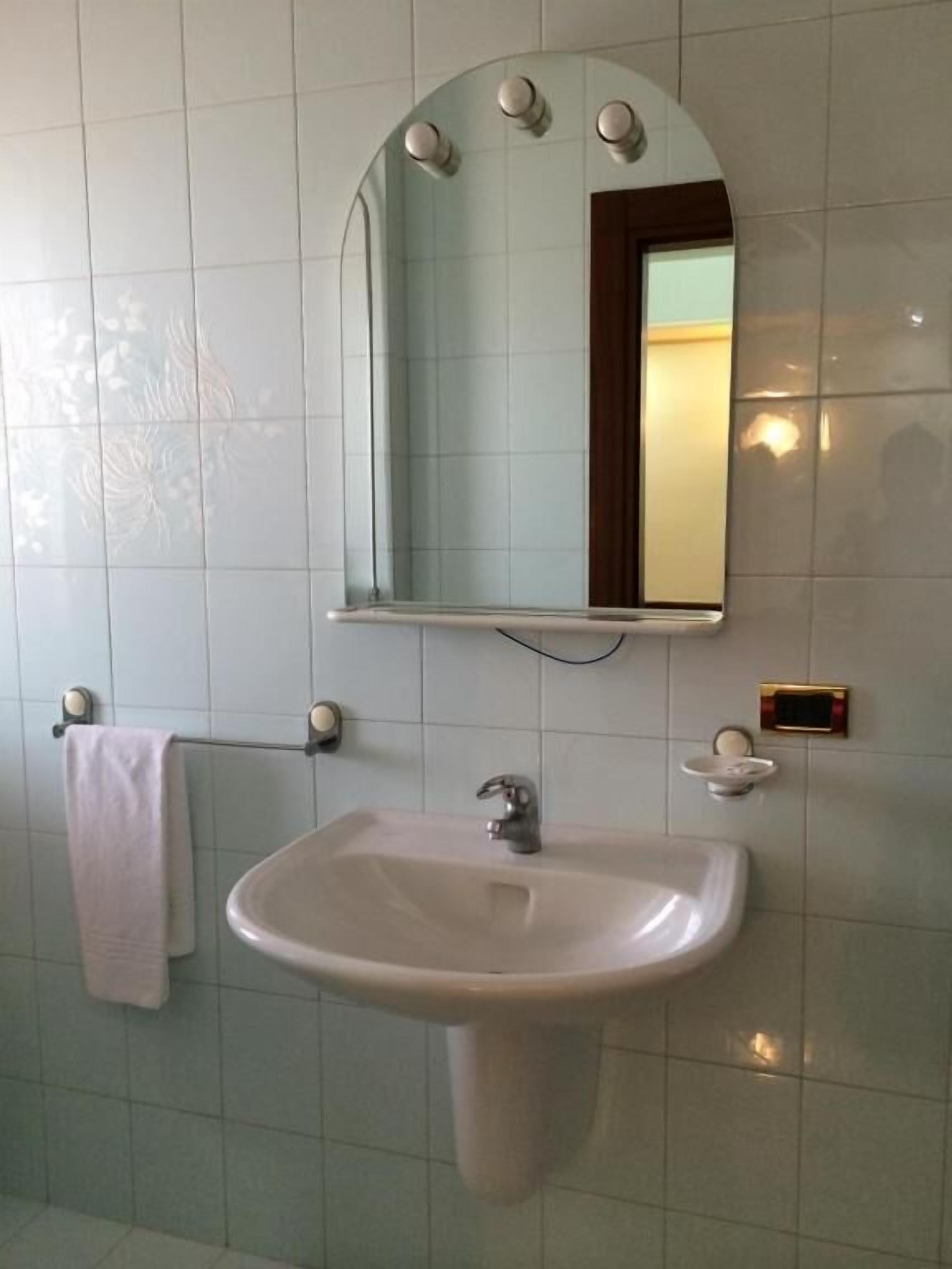 Een badkamer met een witte wastafel, een spiegel en een handdoekhouder.