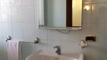 Een badkamer met een witte wastafel, een spiegel en een handdoekhouder.