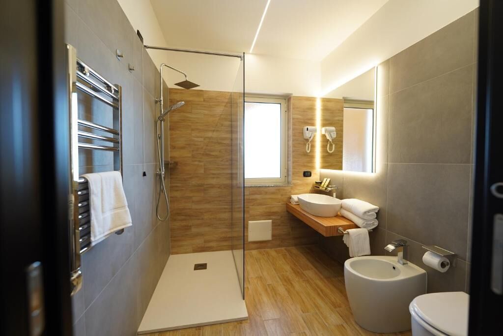 A modern bathroom with a glass shower enclosure, a walk-in shower, a vanity with a sink and mirror, and a toilet.