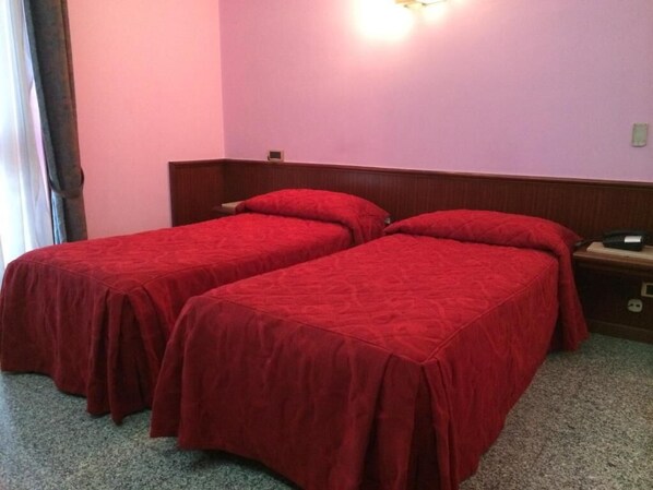 A room with two single beds, each with a red bedspread, a wooden headboard, and a nightstand with a lamp. - Re Di Cuori Hotel (Caianello)